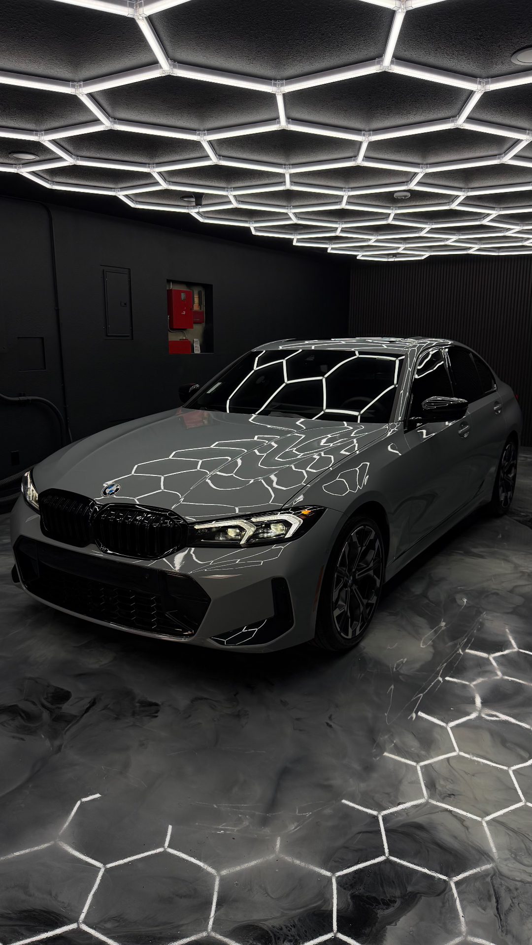 Grey BMW sedan under hex lighting at the Stealth Autowerks studio